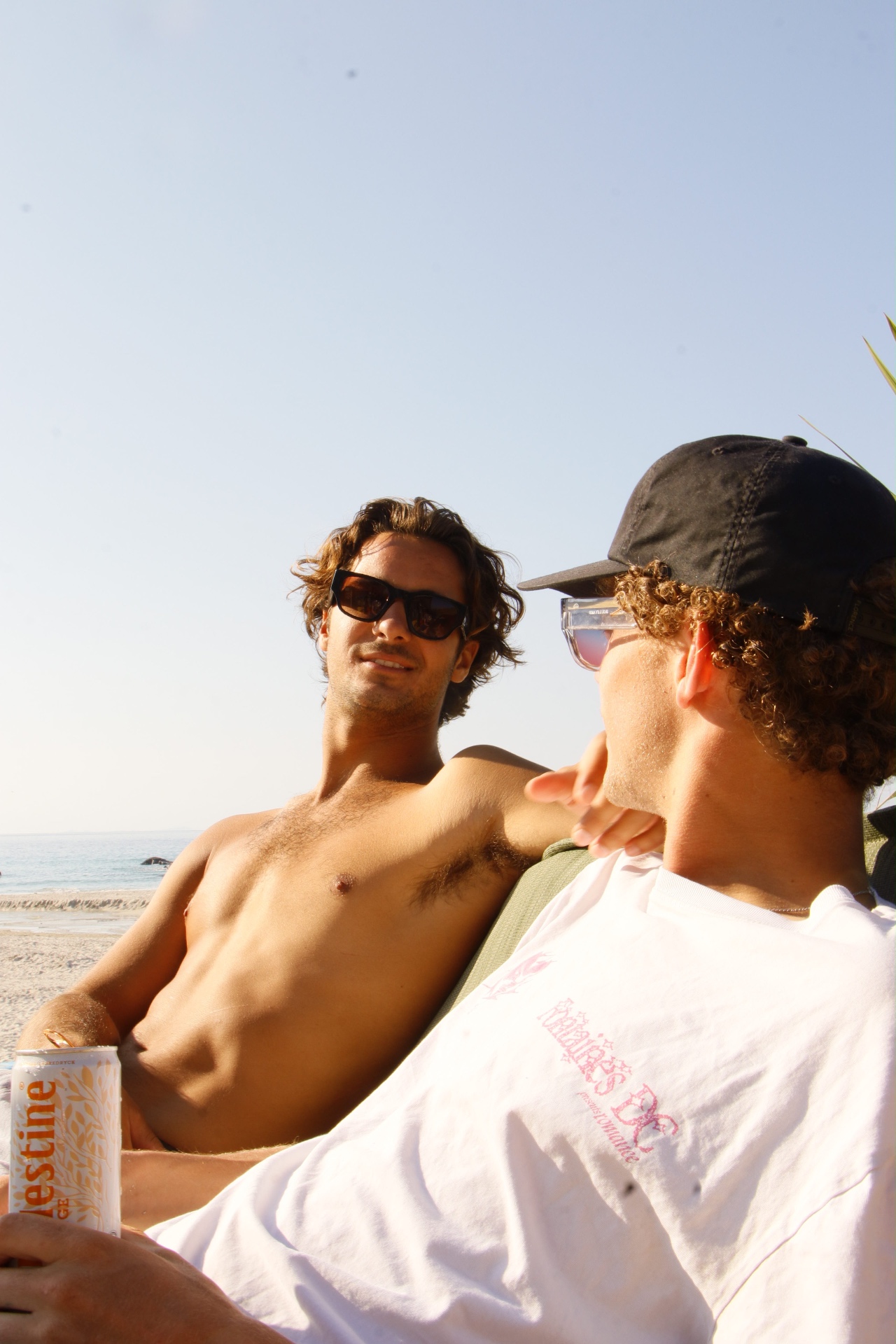 Two friends on the beach wearing TENS sunglasses in late sun