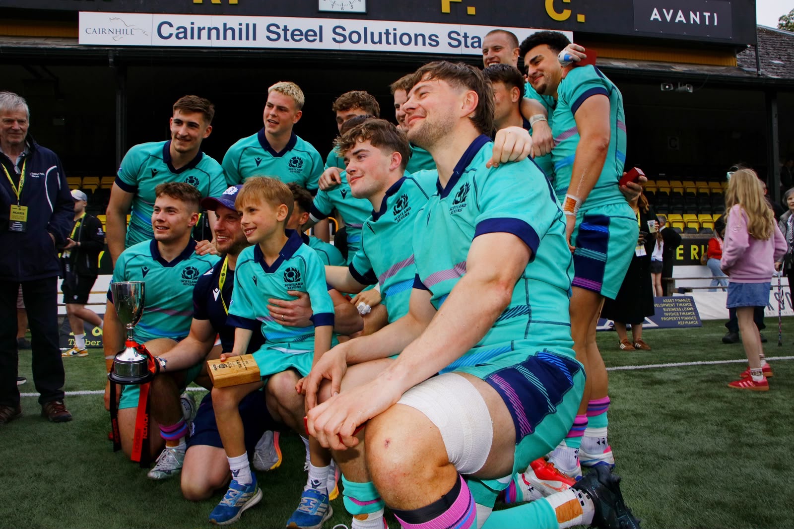 Sevens squad gathered for a team photograph with the trophy on the pitch