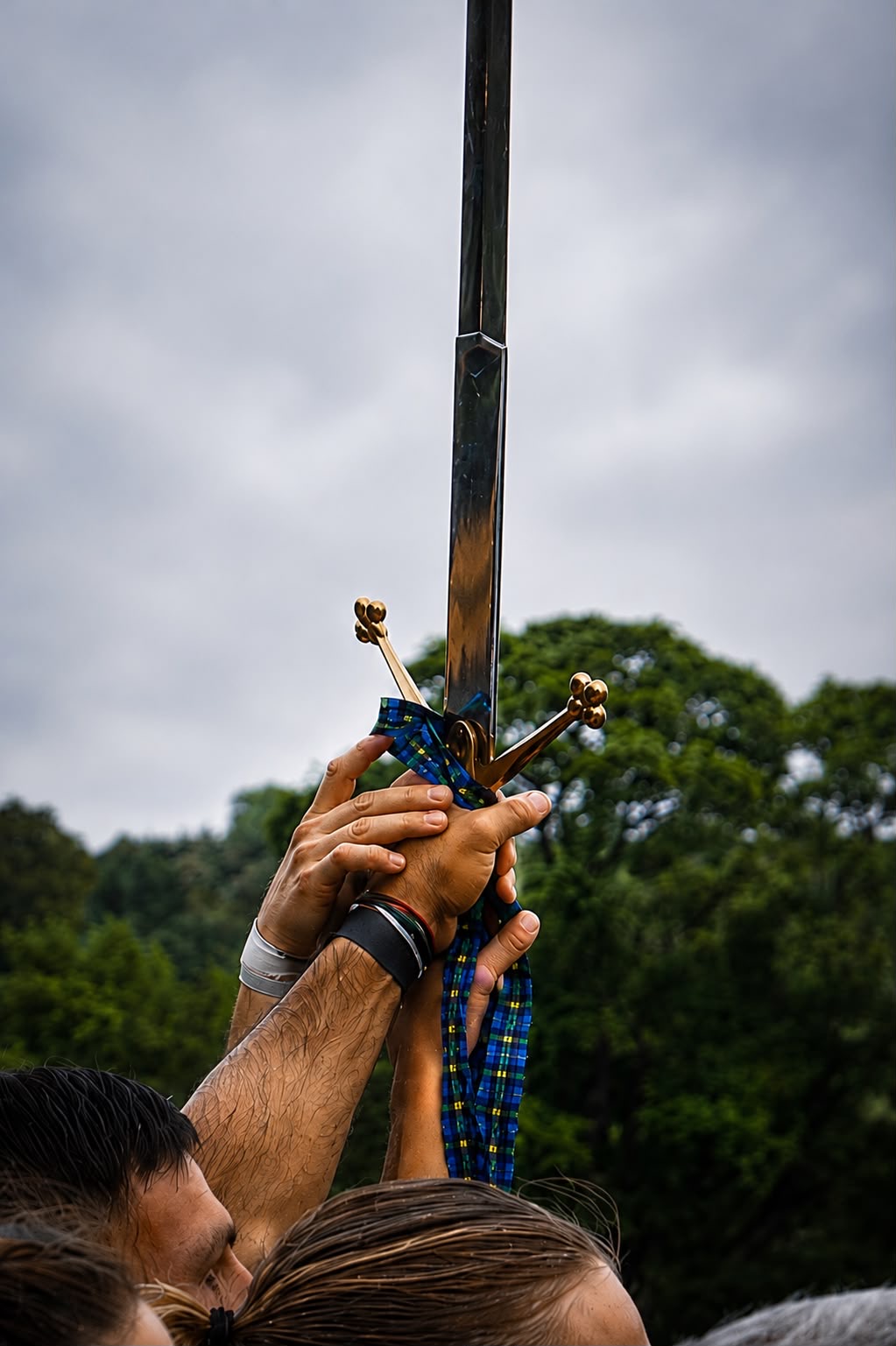 Close-up of hands gripped around the hilt of the raised ceremonial sword