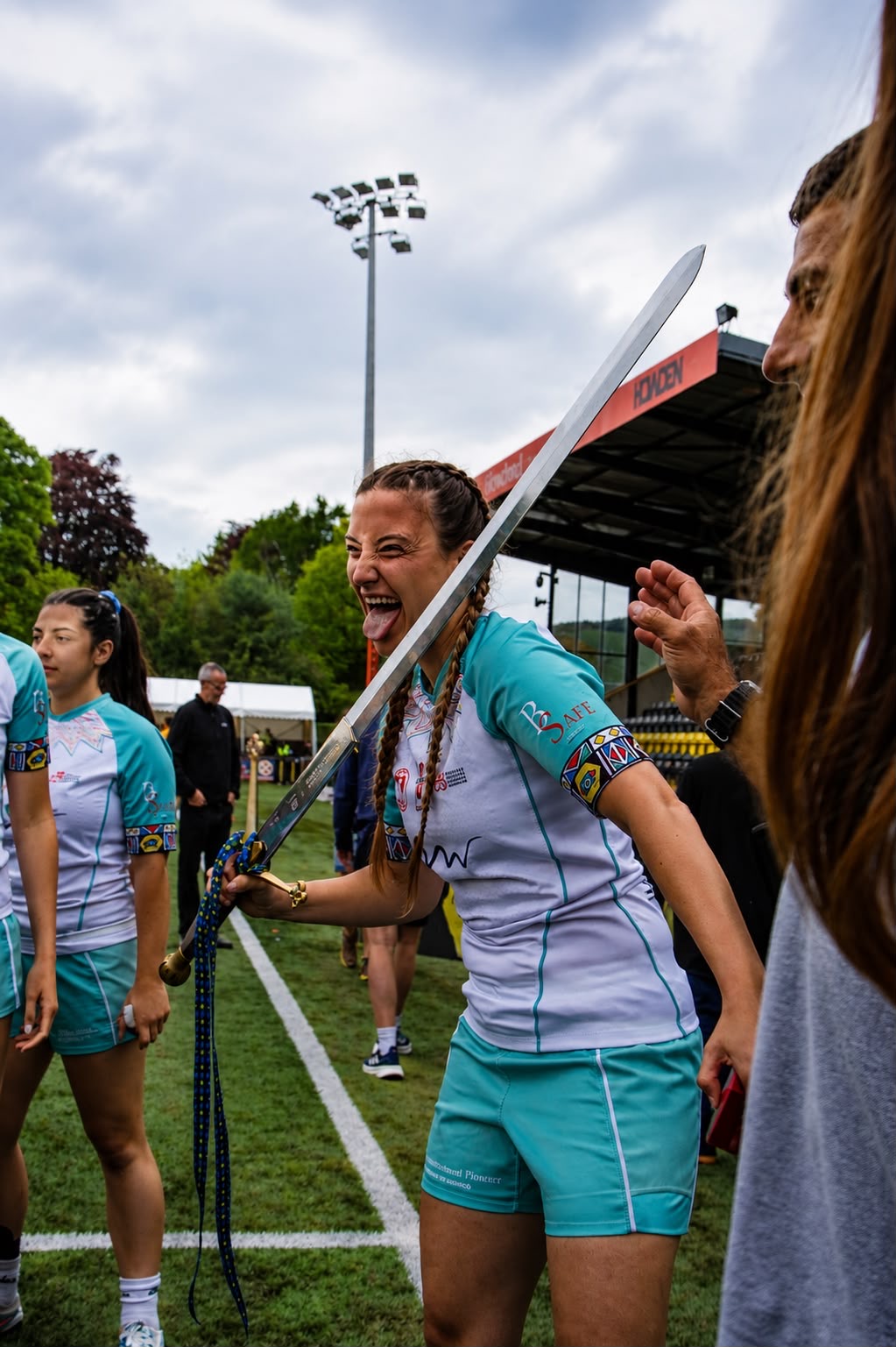 Sevens player laughing on the pitch while holding the ceremonial sword