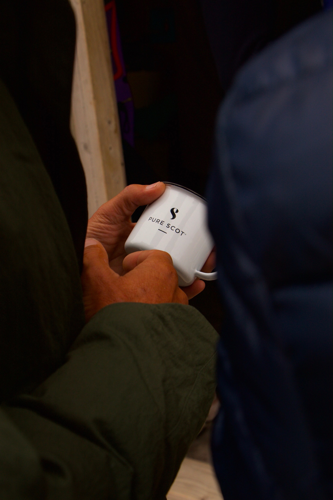 Branded Pure Scot enamel mug held in both hands