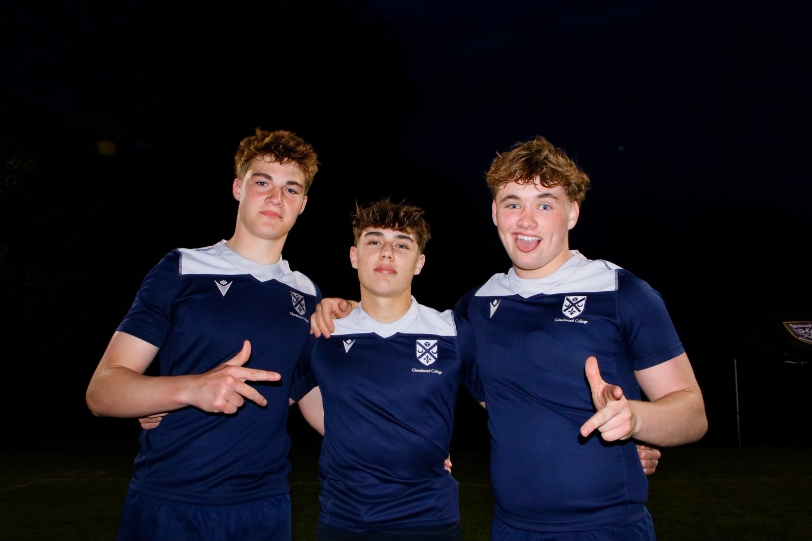 Three young rugby players celebrating together after the final whistle