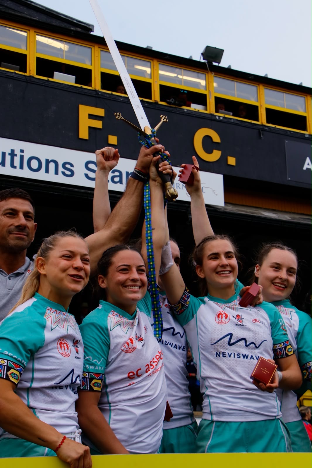 Women's sevens team raising the ceremonial sword in celebration