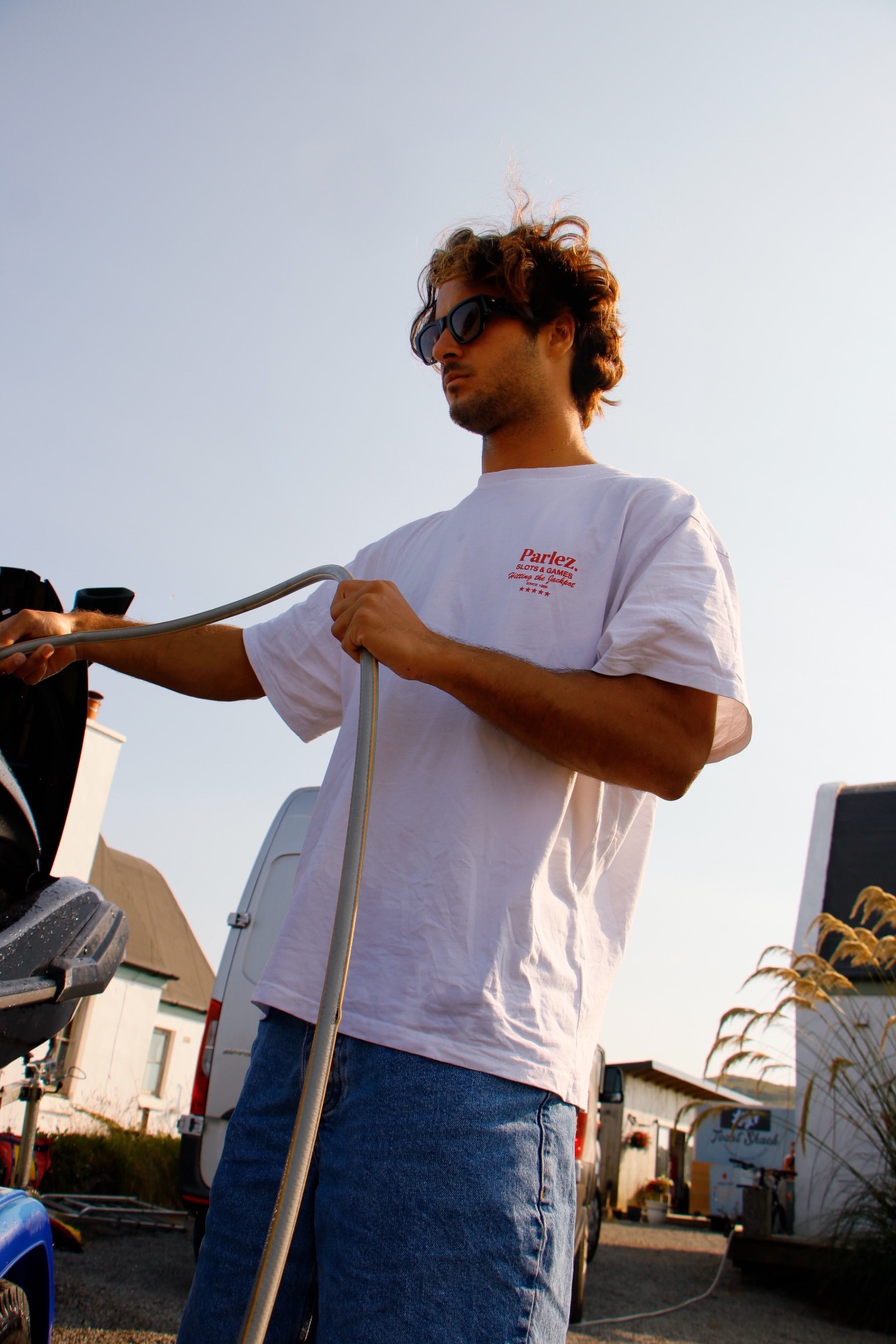 Rider coiling a hose beside the jet ski trailer at golden hour
