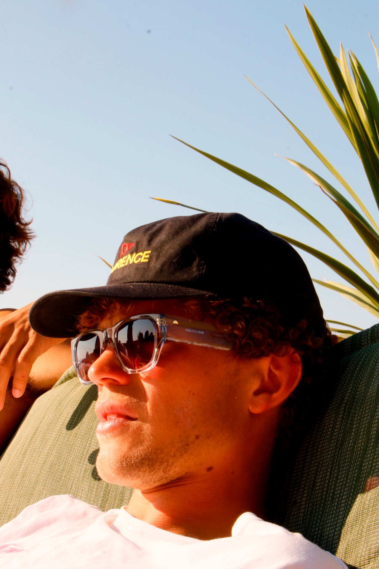 Portrait of a young man in a cap and sunglasses in late afternoon sun