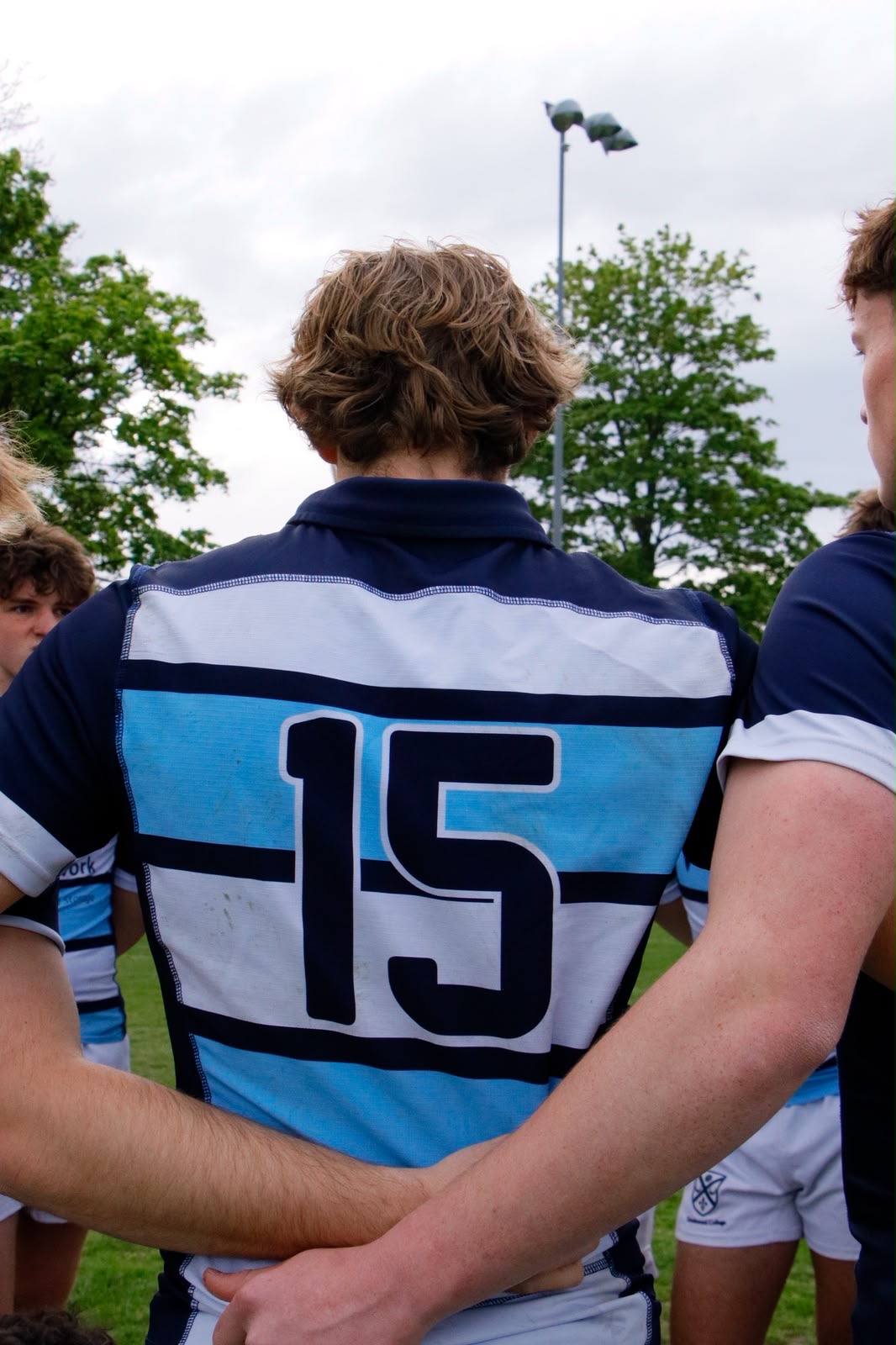 Rugby player number 15 seen from behind in a striped jersey