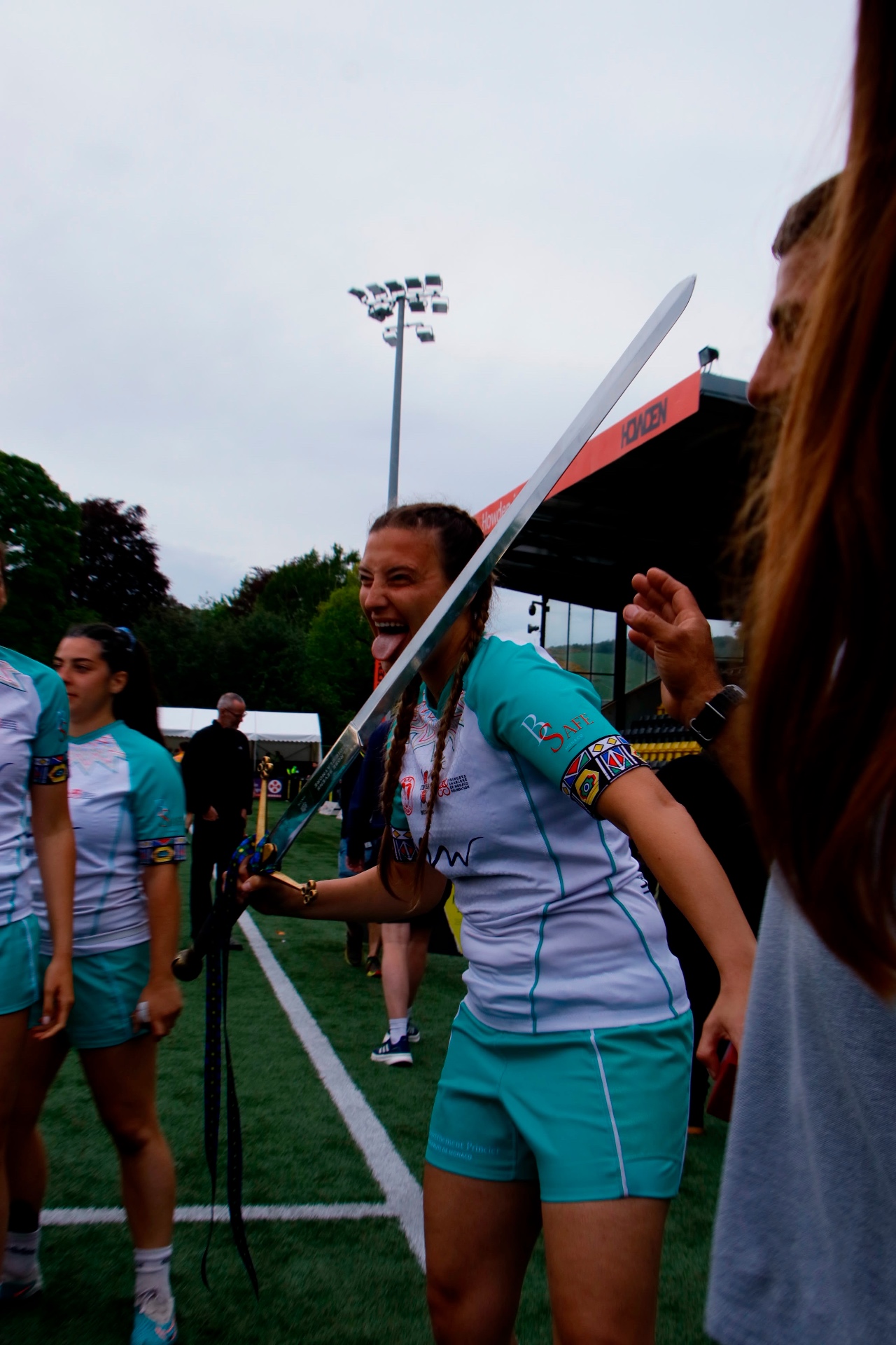 Sevens player pulling a face as she carries the sword off the pitch