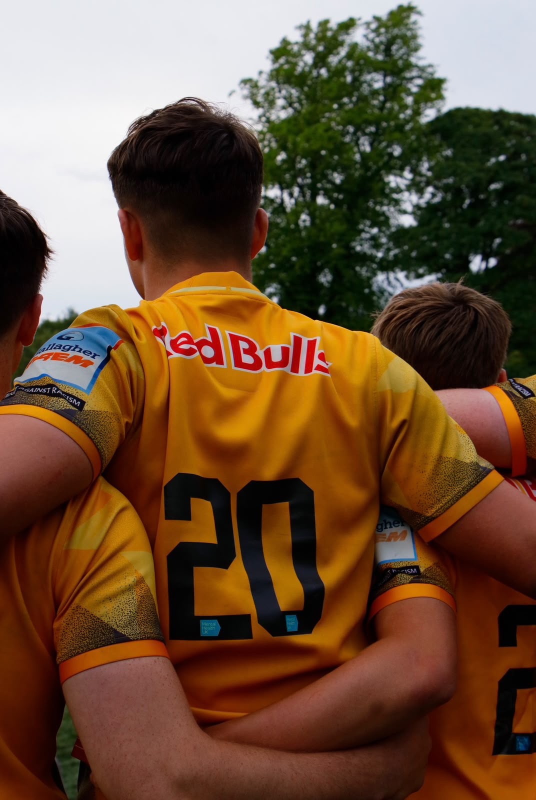 Rugby players in yellow kit arm in arm in a huddle before kick off
